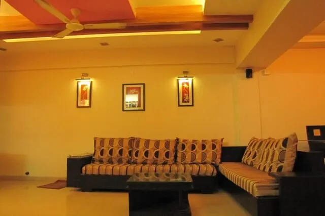 A sitting room with warm yellow walls and patterned sofas.