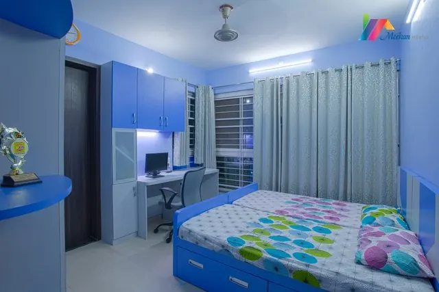 Bedroom with patterned bedding, pale curtains and a television wall.