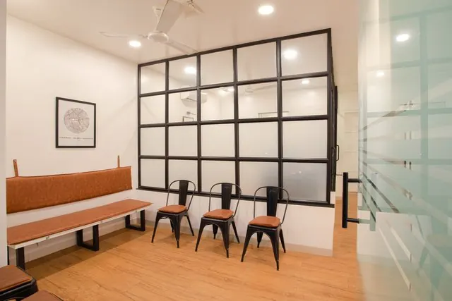 Clinic waiting area with chairs, a timber bench and a glazed partition.