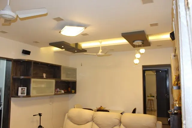 A living room with layered ceiling details, a fan and recessed lighting.