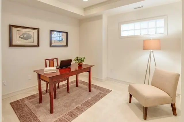 A compact office with a timber desk, upholstered chair and floor lamp.