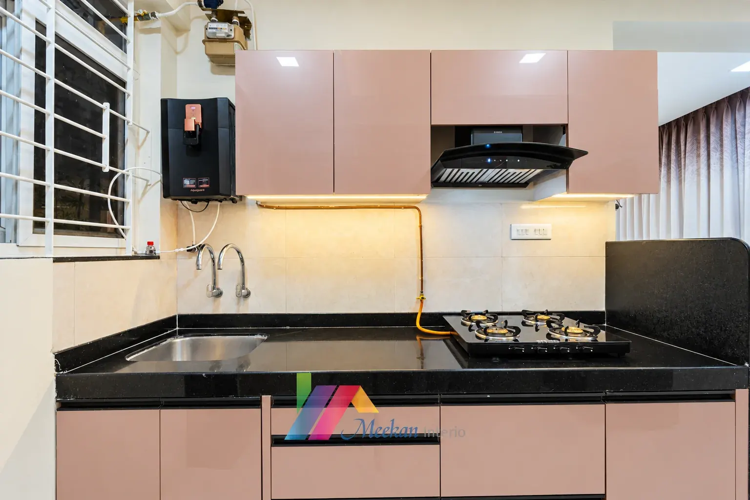Kitchen with pale cabinetry, black worktop, chimney hood and under-cabinet lighting.