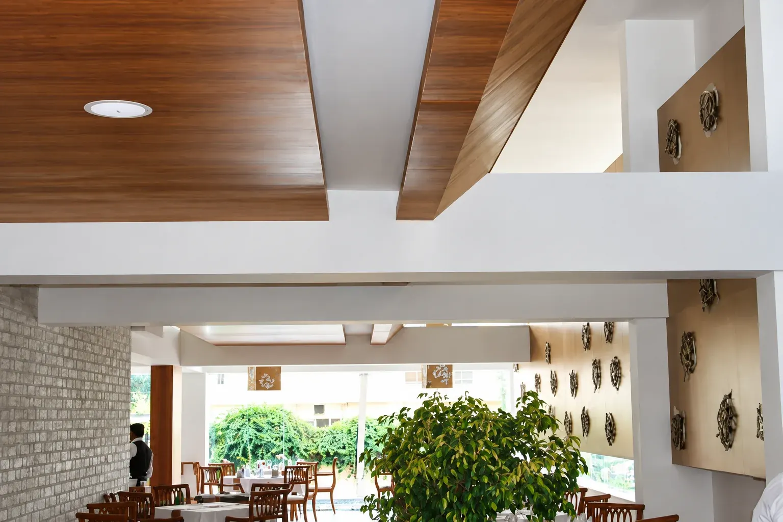 Restaurant interior with timber ceiling panels and a view through to dining tables.