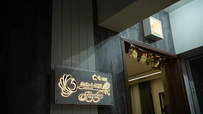 Illuminated entrance nameplate beside a decorated doorway.