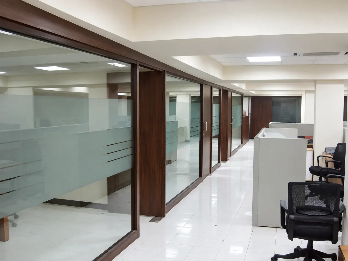 Office corridor with glass partitions and workstations.