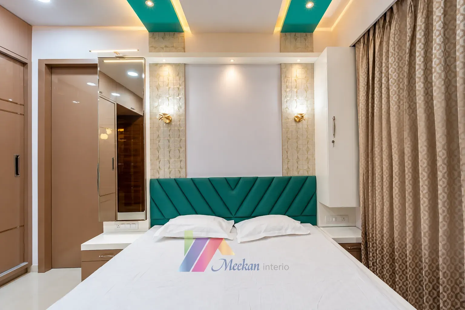 A bedroom with a teal upholstered headboard, patterned wall panels and fitted storage.
