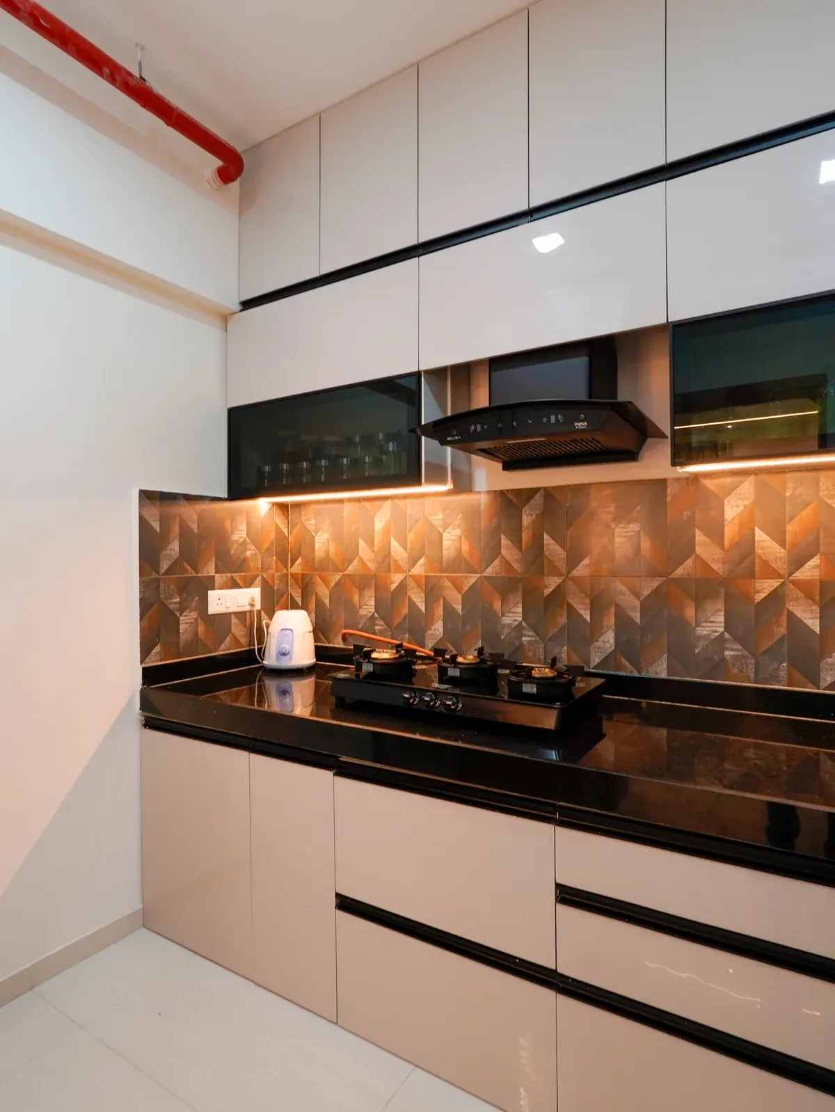 Kitchen with pale cabinets, black worktops and an illuminated geometric backsplash.